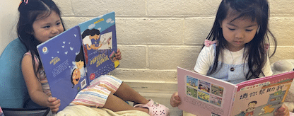 two young girls reading mandarin picture books at language immersion preschool