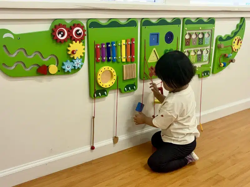 child playing at a montessori inspired sensory activity wall at preschool in albany ca
