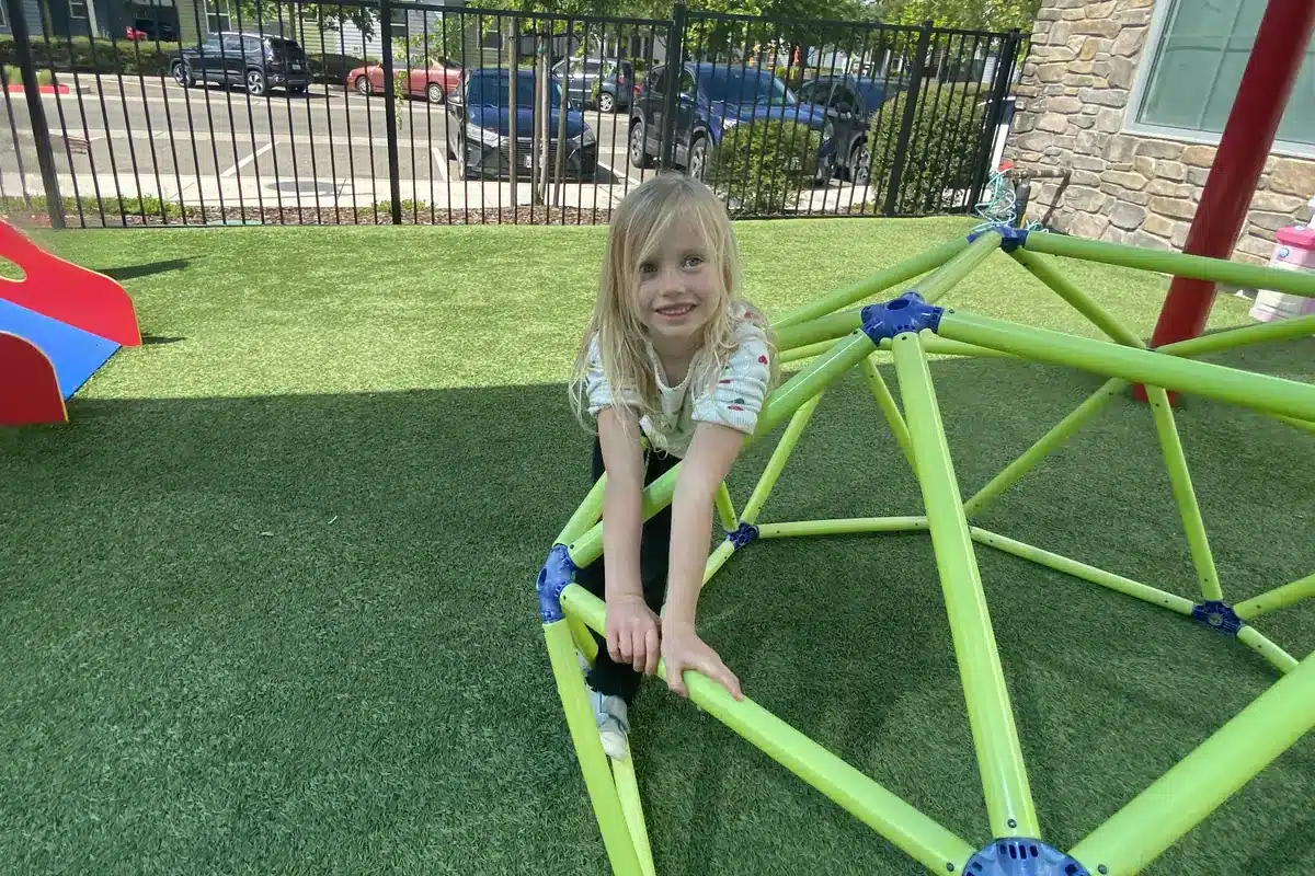 preschool-davis-ca-climbing-dome young girl climbing on the outdoor climbing dome at preschool in davis ca